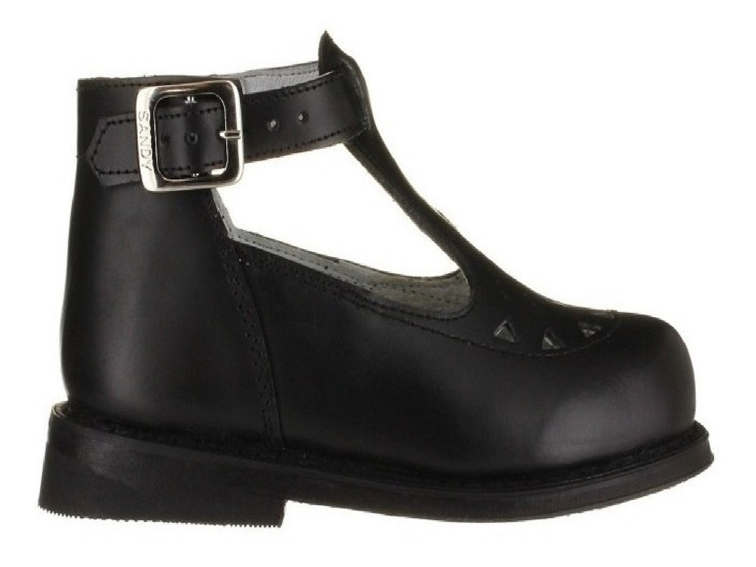 Zapato negro de cuero para niño o niña con correa, hebilla plateada y detalles perforados en la punta.