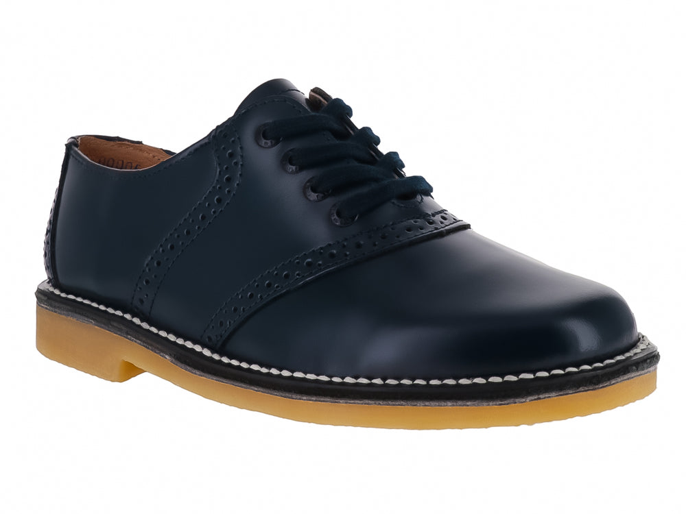 Zapato elegante para niño color marino con suela de goma miel y detalles perforados en el cuero.