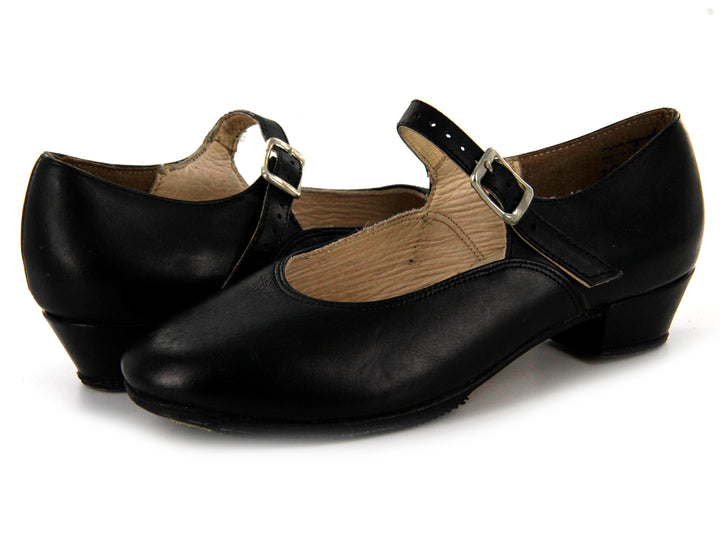 Par de zapatos negros infantiles con correa y hebilla plateada sobre fondo blanco.