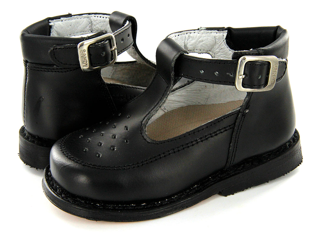 Par de zapatos negros de cuero para niño con correa y hebilla plateada, estilo clásico escolar.