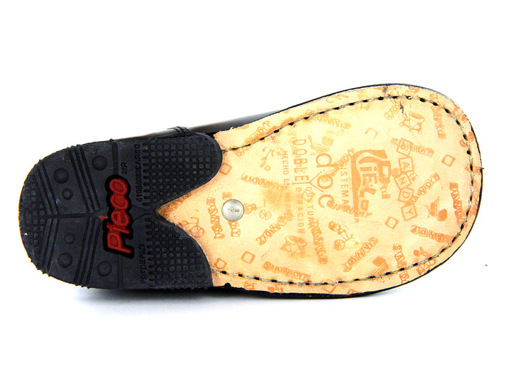 Par de zapatos negros para niño con correa y hebilla plateada, estilo clásico escolar.