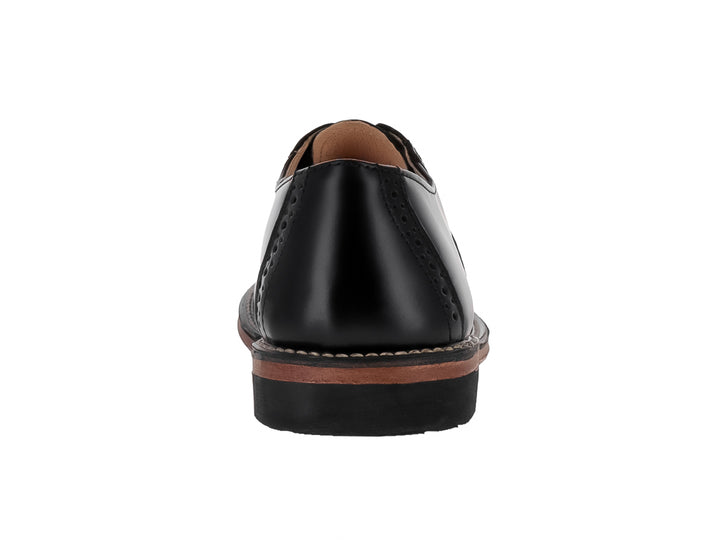 Zapato formal negro de cuero para niño con detalles perforados y suela color café.