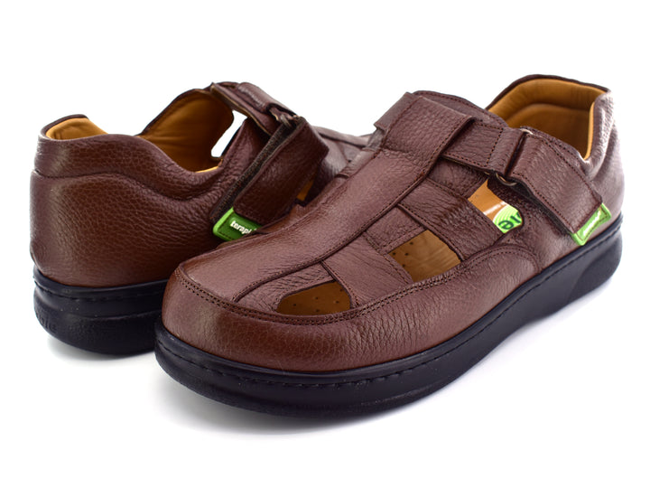 Par de sandalias color café de cuero con suela negra y cierre de velcro.