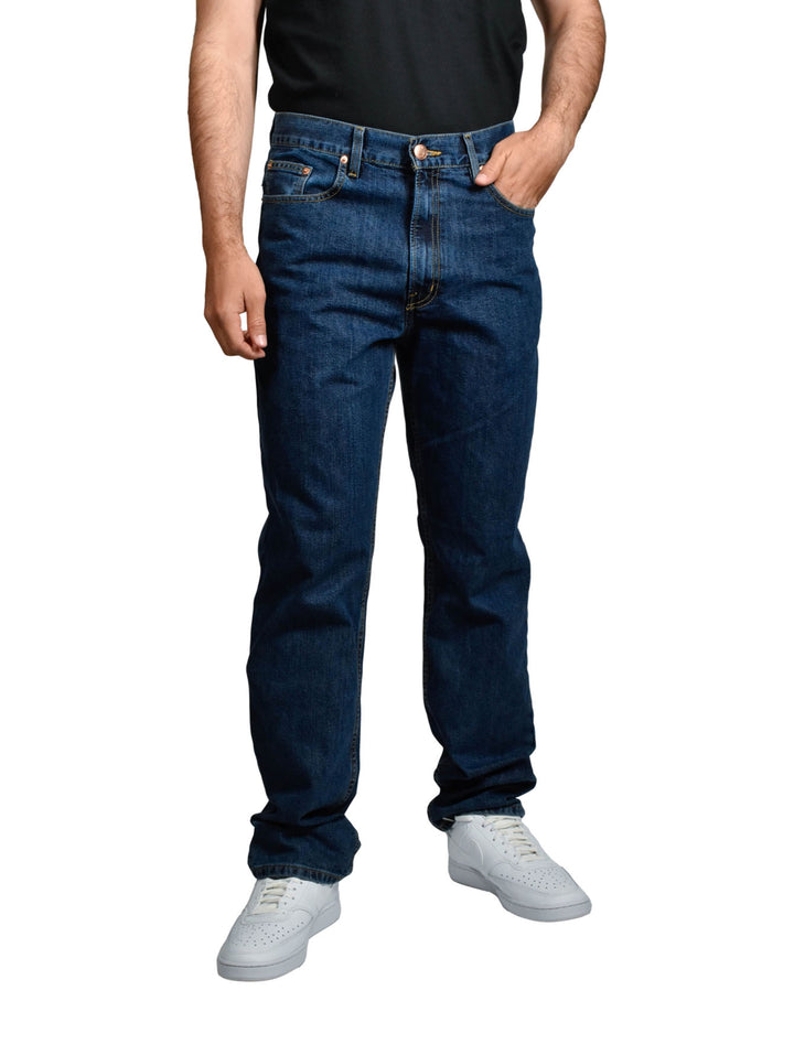 Hombre vistiendo pantalones jeans OGGI de color azul oscuro y tenis blancos sobre fondo blanco.