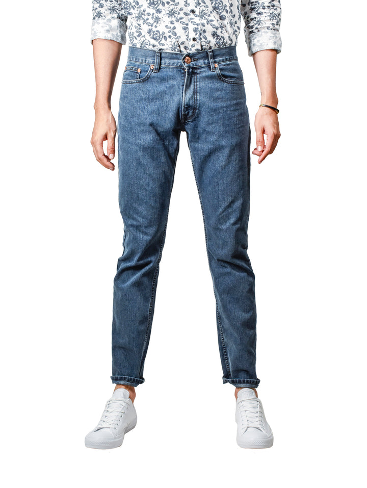 Hombre vistiendo jeans OGGI VAXTER color azul oscuro con tenis blancos.