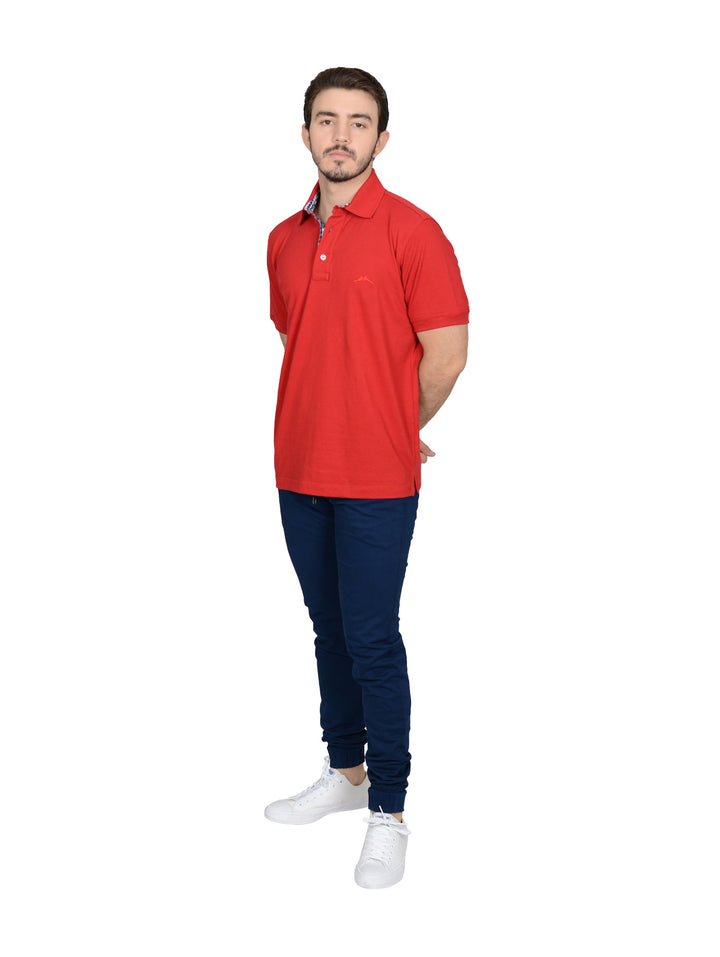 Hombre vistiendo playera polo color rojo quemado con detalle a cuadros en el cuello.