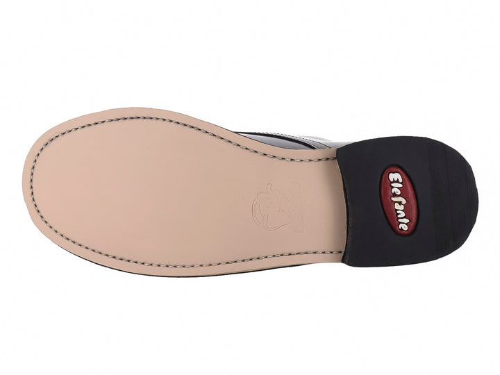 Zapato formal negro de cuero con cordones y suela blanca para niño.