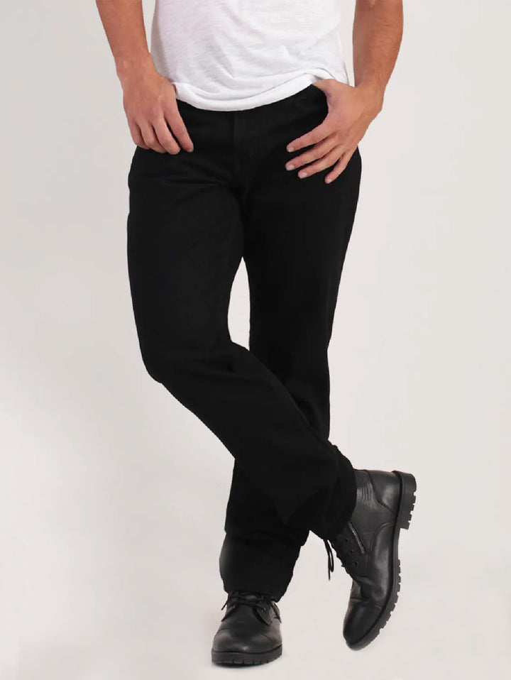 Hombre vistiendo jeans negros de corte recto con camiseta blanca y zapatos negros.