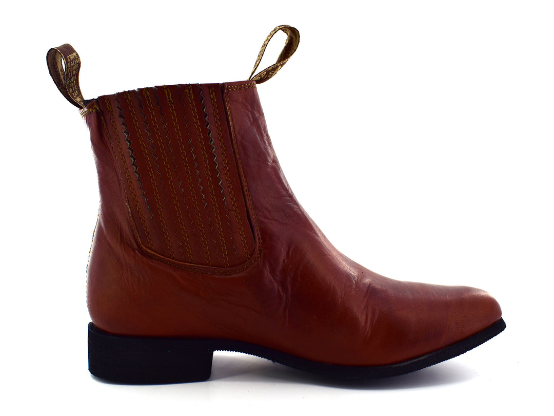Bota estilo Chelsea de cuero color habana con paneles elásticos laterales y suela negra.