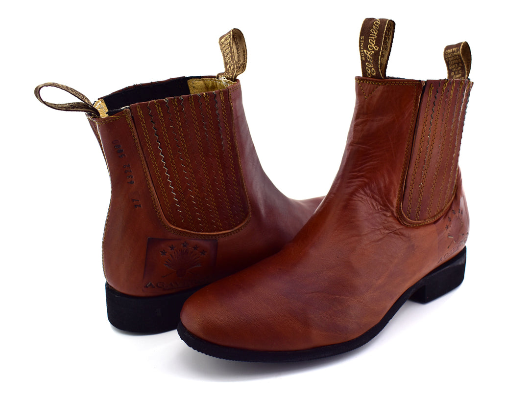 Bota estilo Chelsea de cuero color habana con paneles elásticos laterales y suela negra.