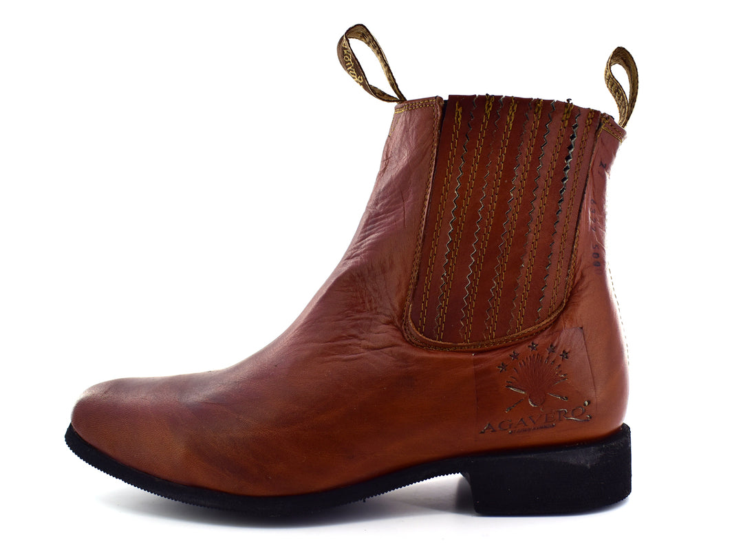 Bota estilo Chelsea de cuero color habana con paneles elásticos laterales y suela negra.