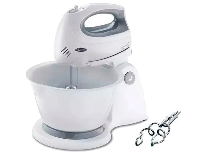 Batidora de pedestal Oster blanca con tazón y accesorios de batido metálicos.