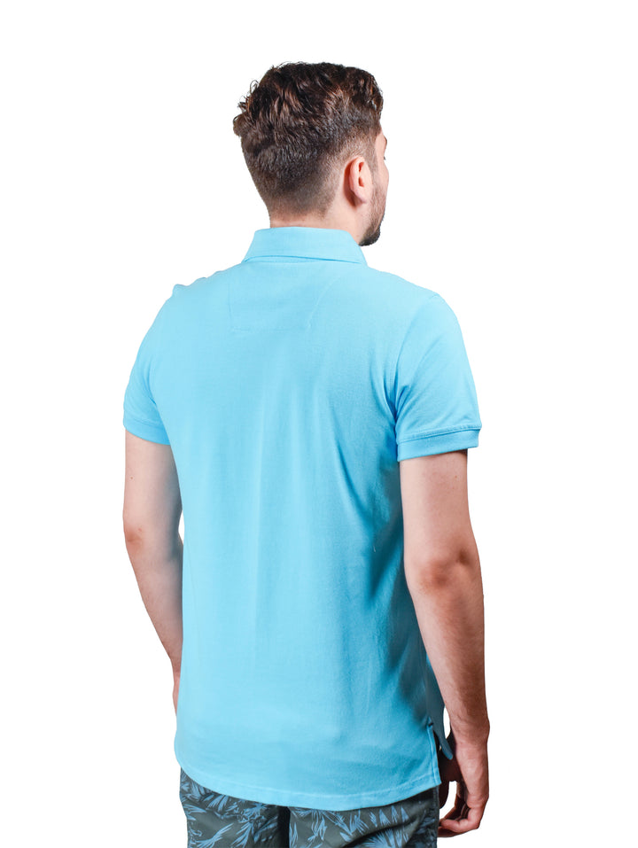 Hombre vistiendo playera polo de color esmeralda de la marca White Peak.