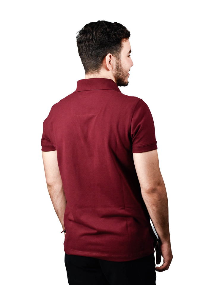 Hombre vistiendo una playera polo color tinto de manga corta.