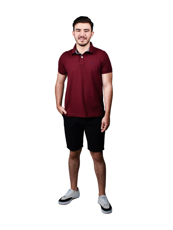 Hombre vistiendo una playera polo color tinto de manga corta.