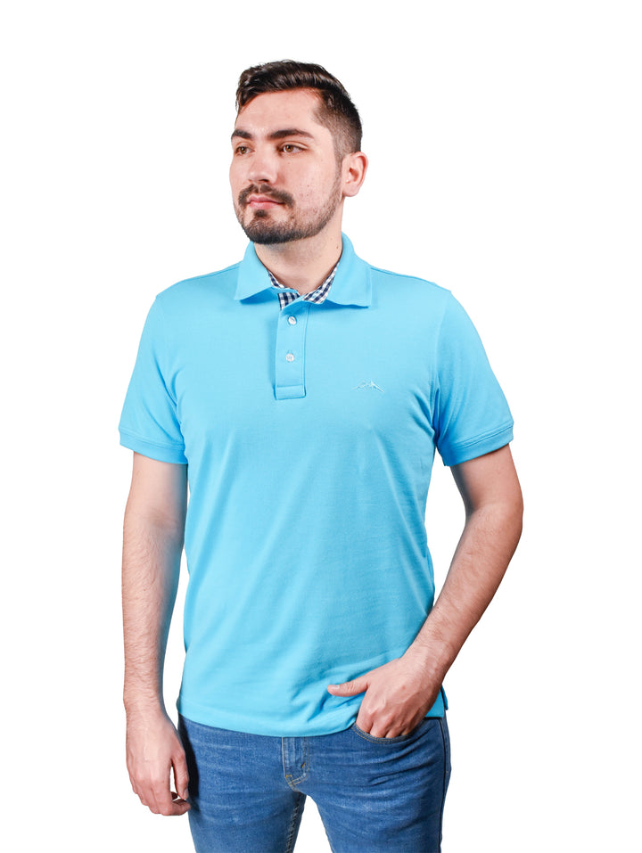 Hombre vistiendo playera polo color azul aqua con cuello estampado y pantalones vaqueros azules.