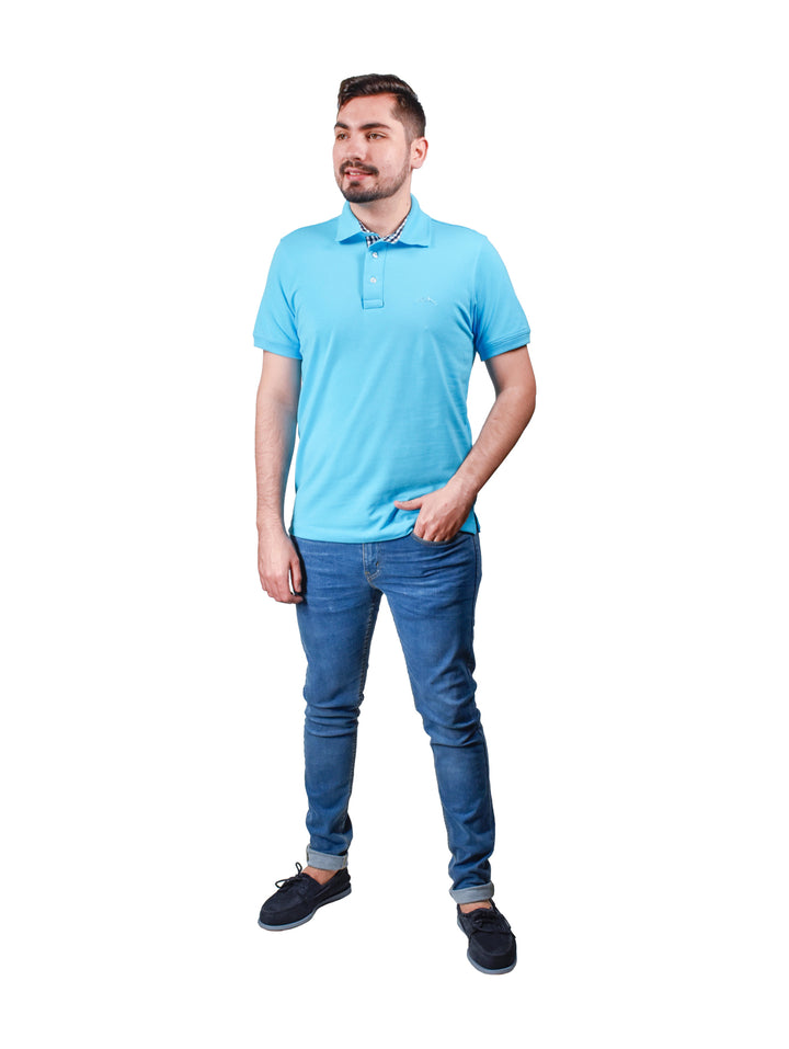 Hombre vistiendo playera polo color azul aqua con cuello estampado y pantalones vaqueros azules.