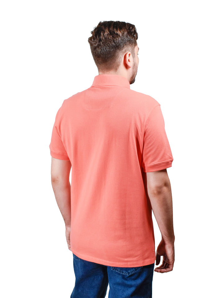 Hombre vistiendo una playera polo color coral de manga corta con detalle en el cuello.
