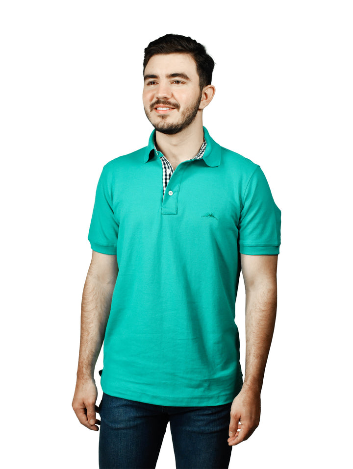 Hombre usando playera polo color esmeralda con detalle a cuadros en el cuello.