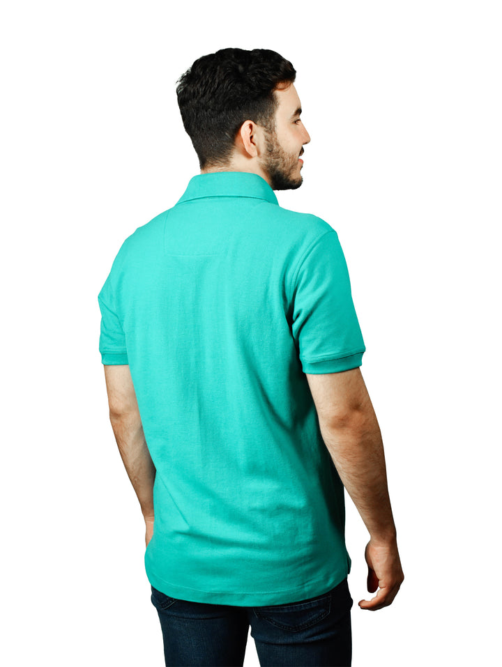 Hombre usando playera polo color esmeralda con detalle a cuadros en el cuello.