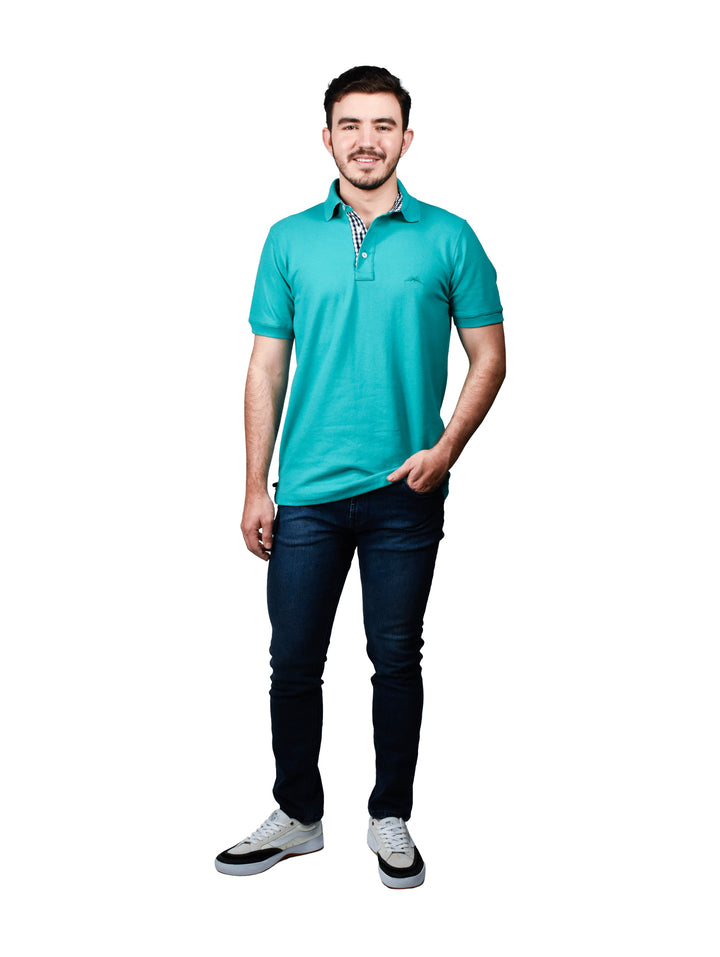 Hombre usando playera polo color esmeralda con detalle a cuadros en el cuello.