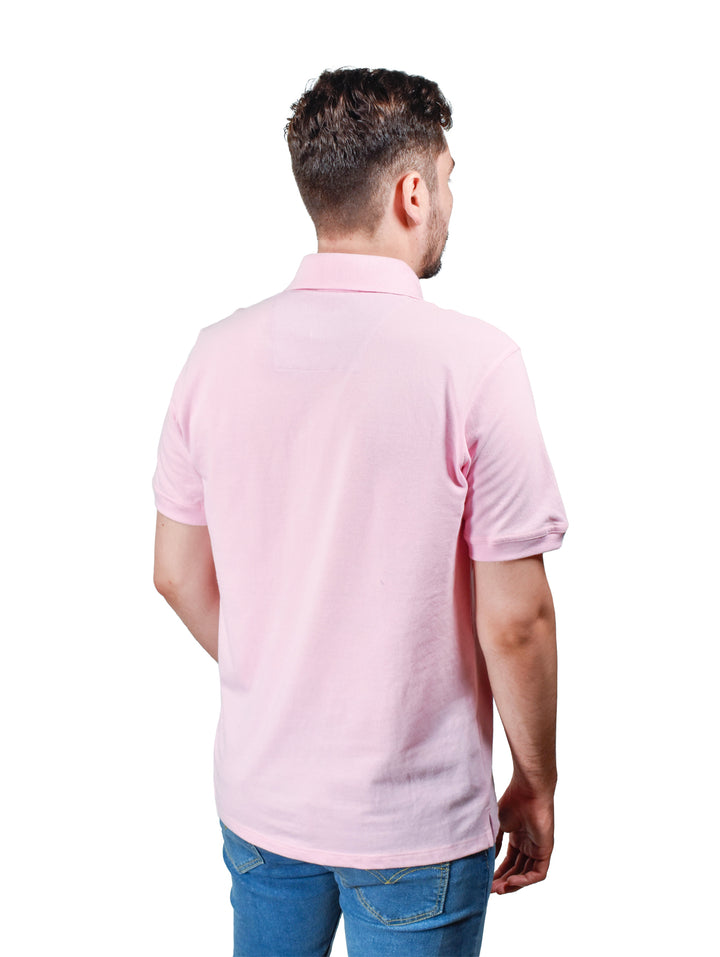 Hombre usando una playera polo color rosa de manga corta y cuello con botones.