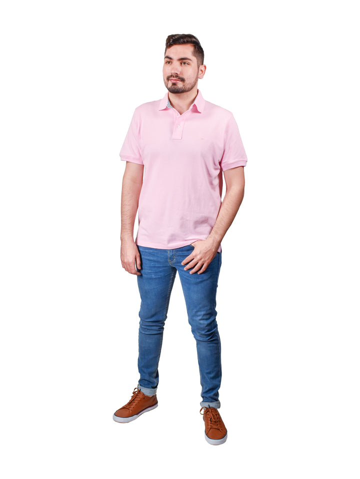 Hombre usando una playera polo color rosa de manga corta y cuello con botones.