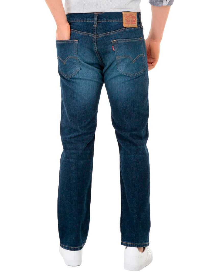 Hombre vistiendo jeans Levi's 505 de color azul oscuro y tenis blancos.