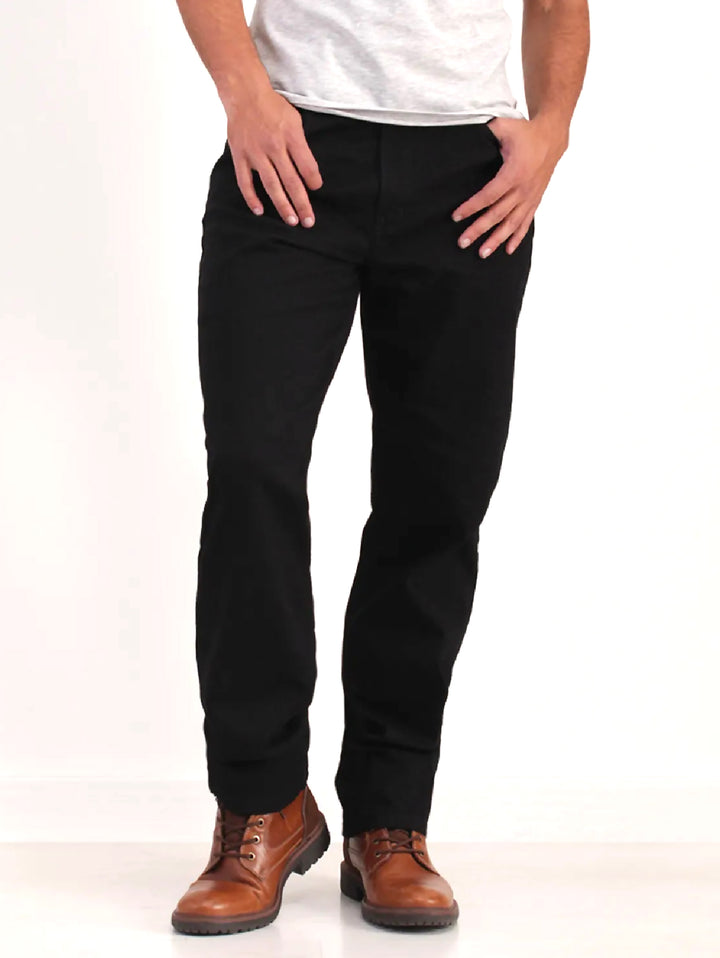 Hombre vistiendo pantalones jeans color negro de corte recto y botas cafés.
