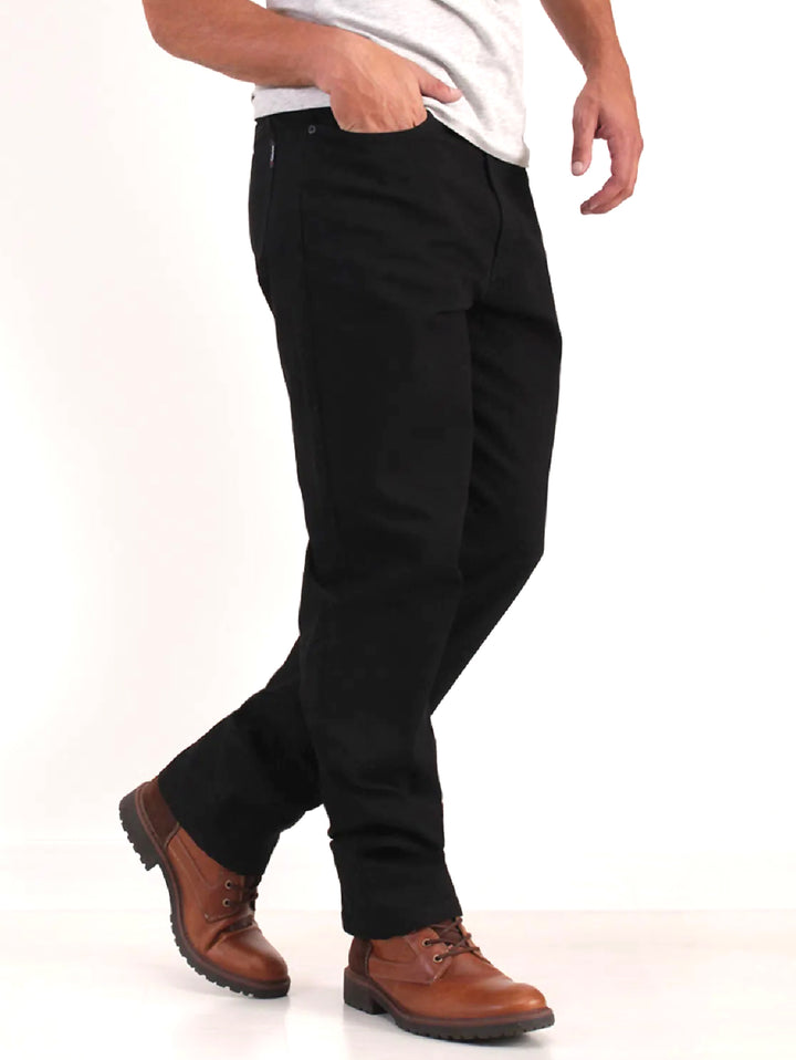 Hombre vistiendo pantalones jeans color negro de corte recto y botas cafés.
