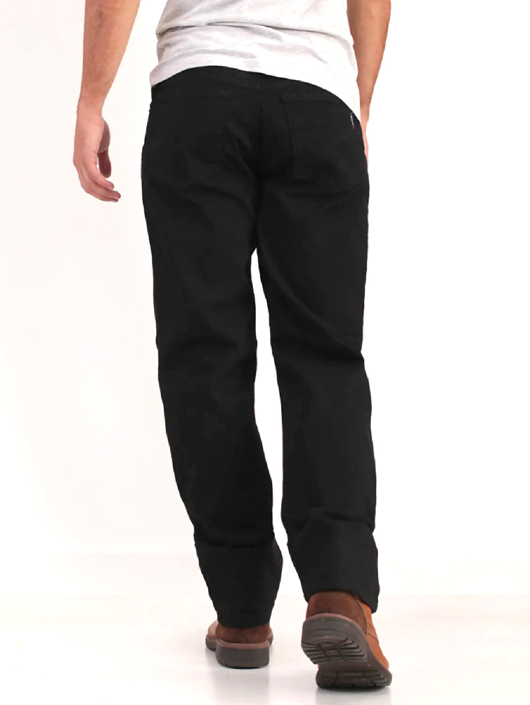 Hombre vistiendo pantalones jeans color negro de corte recto y botas cafés.