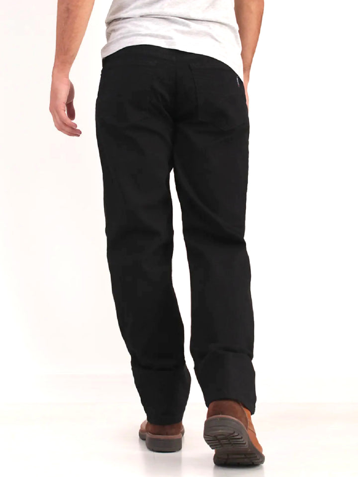 Hombre vistiendo pantalones jeans color negro de corte recto y botas cafés.