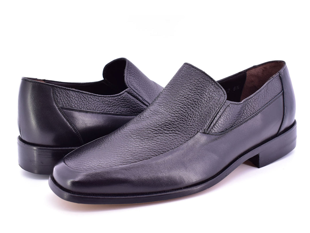 Par de zapatos planos negros de cuero con textura combinada, estilo elegante y sin cordones.
