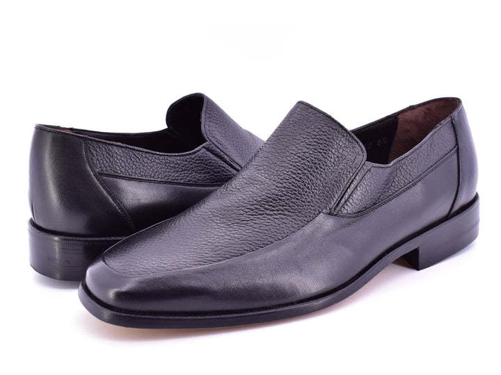 Par de zapatos planos negros de cuero con textura combinada, estilo elegante y sin cordones.
