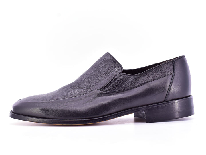 Par de zapatos planos negros de cuero con textura combinada, estilo elegante y sin cordones.