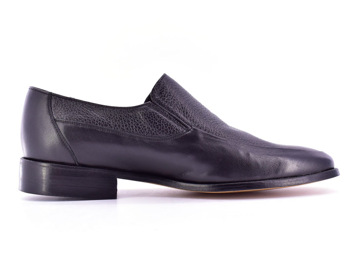 Par de zapatos planos negros de cuero con textura combinada, estilo elegante y sin cordones.