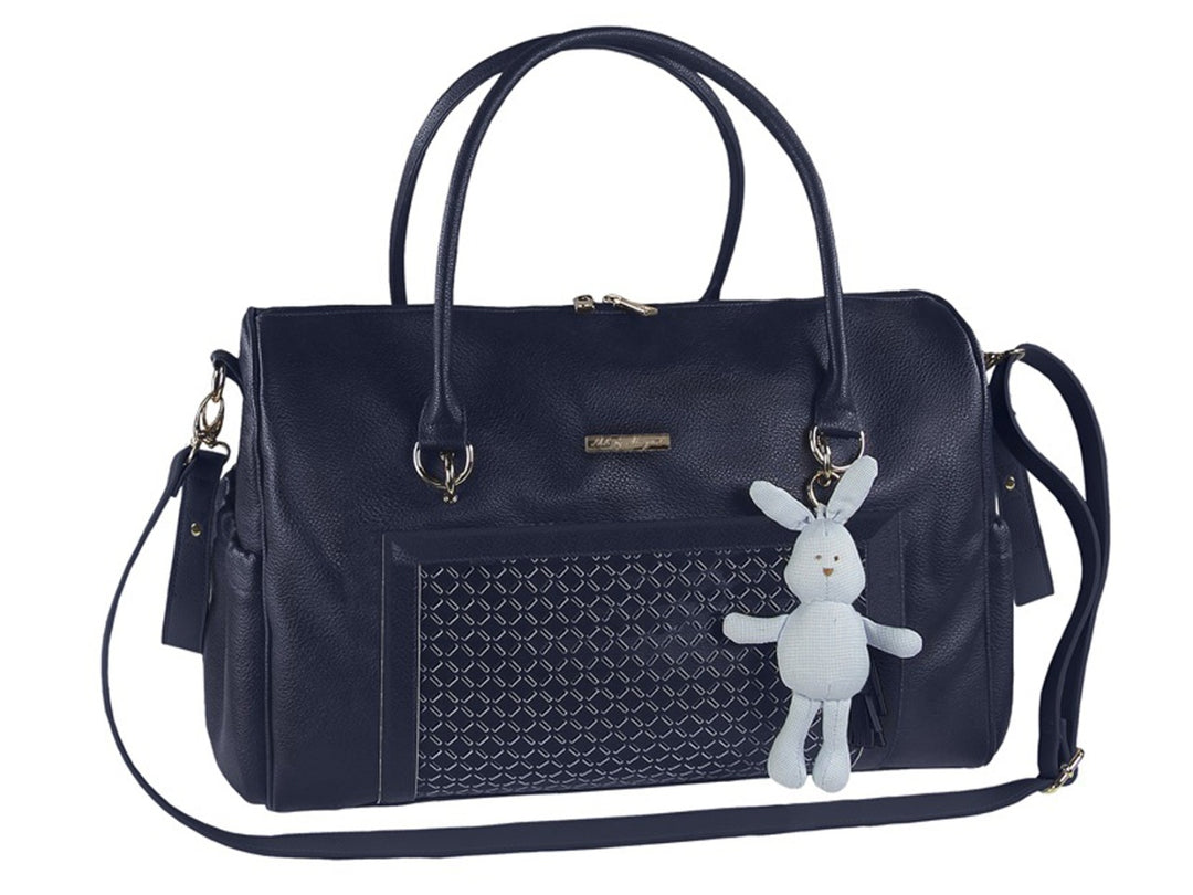 Bolso tipo pañalera color azul marino con asas, correa larga y un pequeño peluche de conejo blanco colgando.
