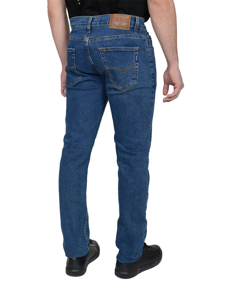 Hombre vistiendo pantalones jeans azules de corte ajustado y calzado negro.