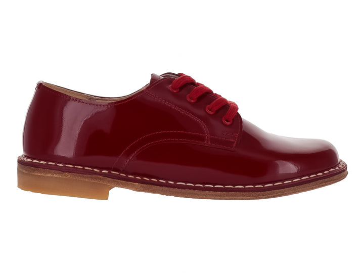 Zapato infantil de charol color rojo brillante con agujetas y costuras blancas en la suela.