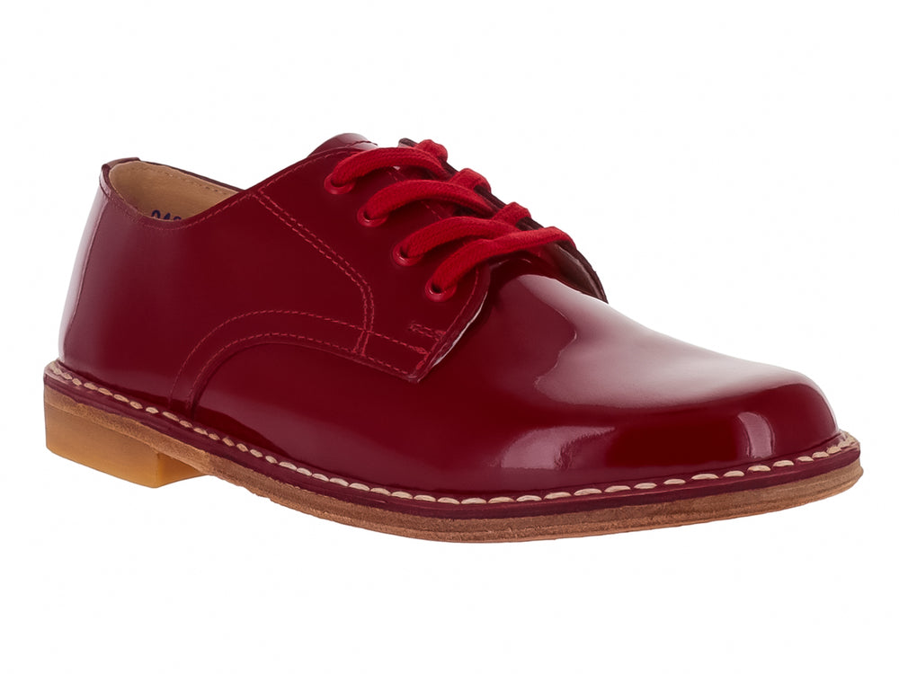 Zapato infantil de charol color rojo brillante con agujetas y costuras blancas en la suela.