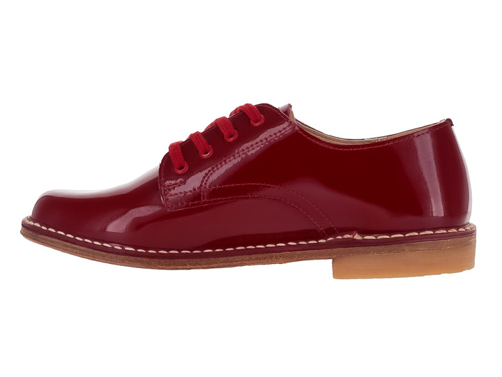 Zapato infantil de charol color rojo brillante con agujetas y costuras blancas en la suela.