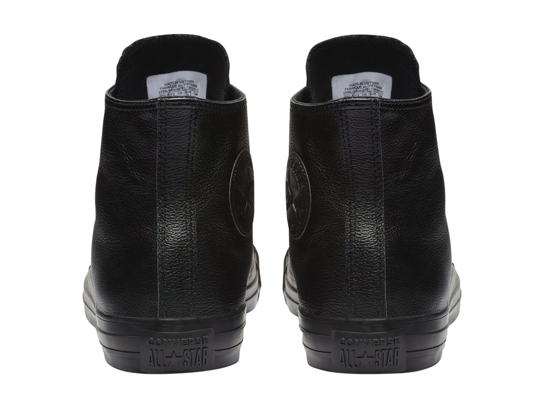 Tenis Converse Chuck Taylor de cuero negro, modelo bota con agujetas y suela negra.