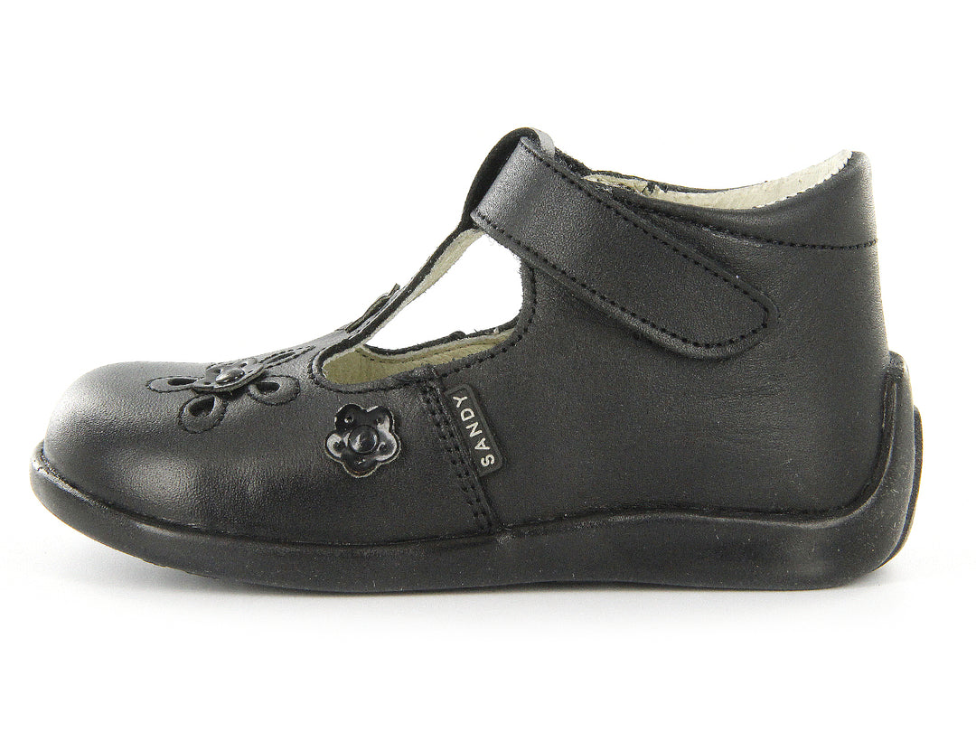 Par de zapatos negros para niña con detalles de flores en relieve y cierre de correa con velcro.
