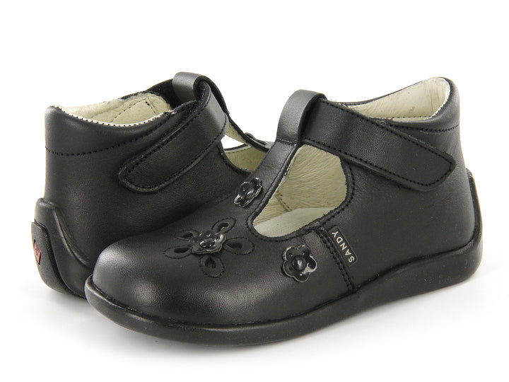 Par de zapatos negros para niña con correa de velcro y detalles de flores en relieve sobre el empeine.