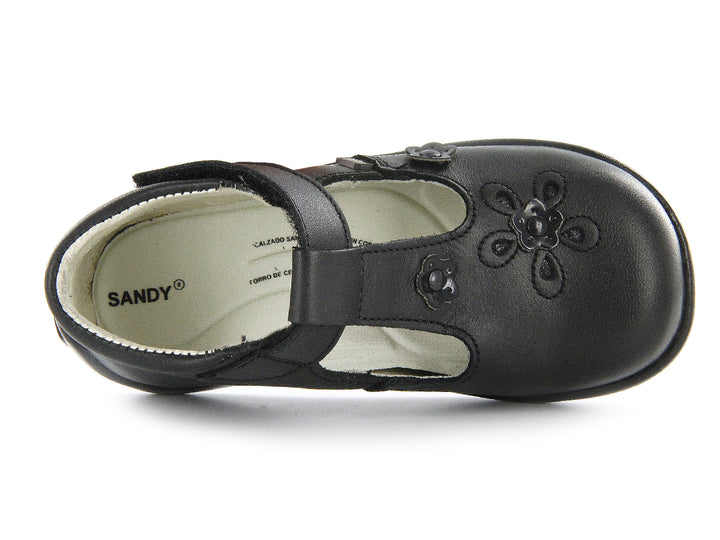 Par de zapatos negros para niña con correa de velcro y detalles de flores en relieve sobre el empeine.