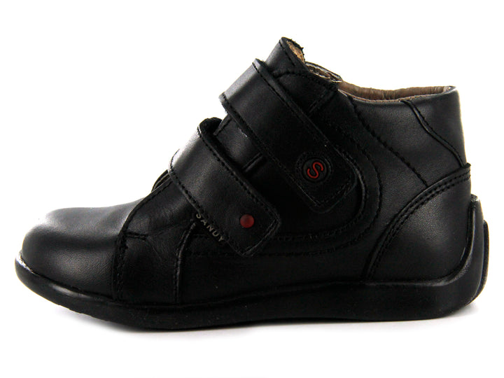 Par de zapatos negros para niño de material sintético o cuero con cierre de doble correa de velcro.