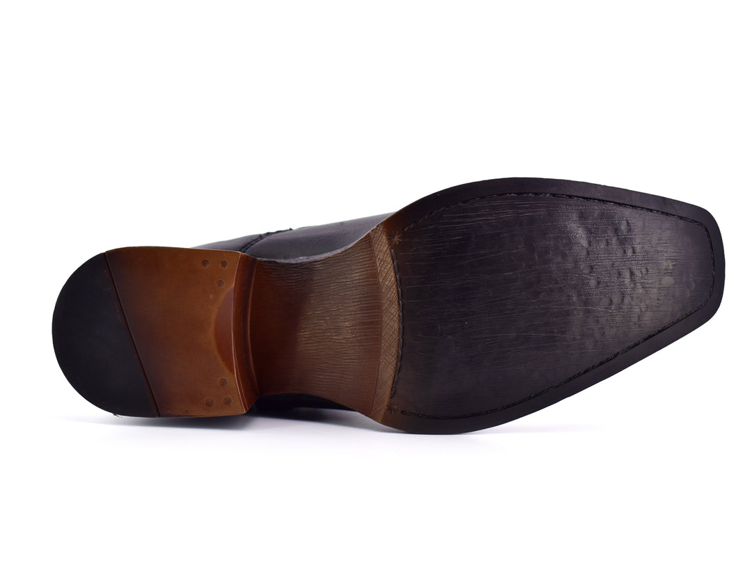 Botines negros para hombre con hebilla y remaches plateados sobre fondo blanco.