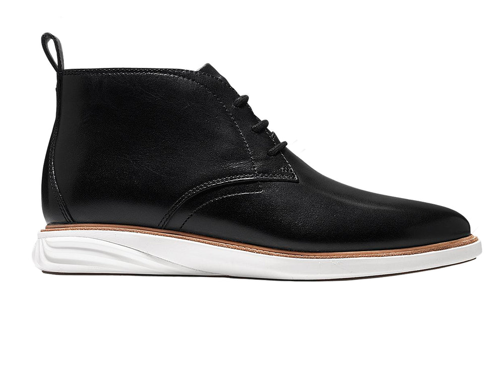 Par de botas chukka de cuero negro con suela blanca y cordones.