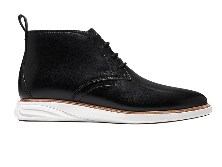 Par de botas chukka de cuero negro con suela blanca y cordones.