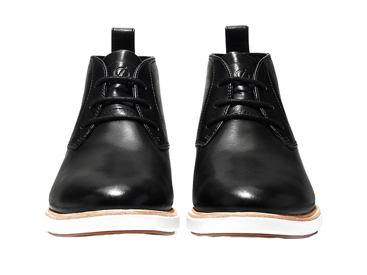 Par de botas chukka de cuero negro con suela blanca y cordones.